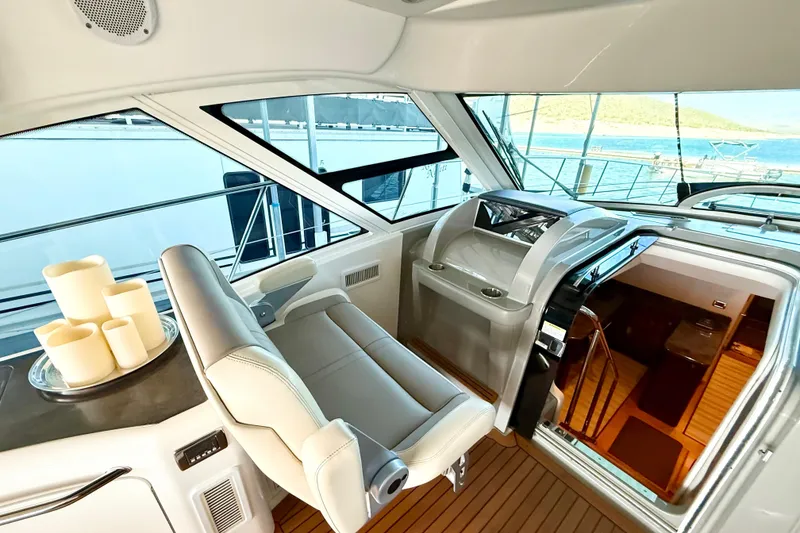Slide: The Image of 2014 Sea Ray 580 Sundancer yacht interior with helm, luxury seating, and scenic ocean view. - 13