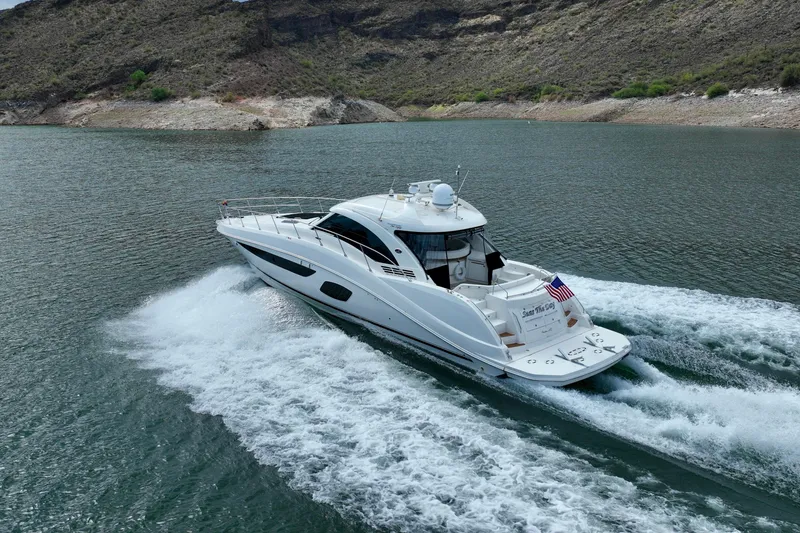 Slide: The Image of 2014 Sea Ray 580 Sundancer cruising on a scenic lake with rocky shoreline. - 3