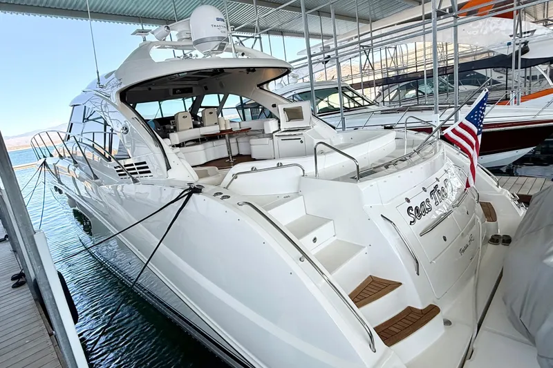 Slide: The Image of 2014 Sea Ray 580 Sundancer yacht docked, featuring sleek design and American flag. - 5