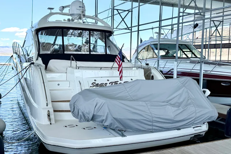 Slide: The Image of 2014 Sea Ray 580 Sundancer yacht docked, covered boat on deck, American flag displayed. - 66