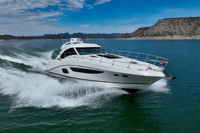 Slide: The Image of 2014 Sea Ray 580 Sundancer yacht cruising on a scenic lake under a clear blue sky. - 68