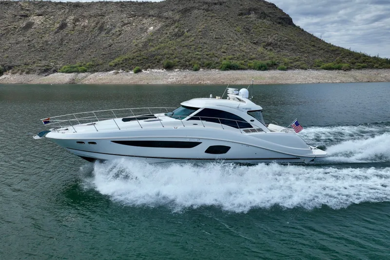 Slide: The Image of 2014 Sea Ray 580 Sundancer yacht cruising on a scenic lake with hills in the background. - 72