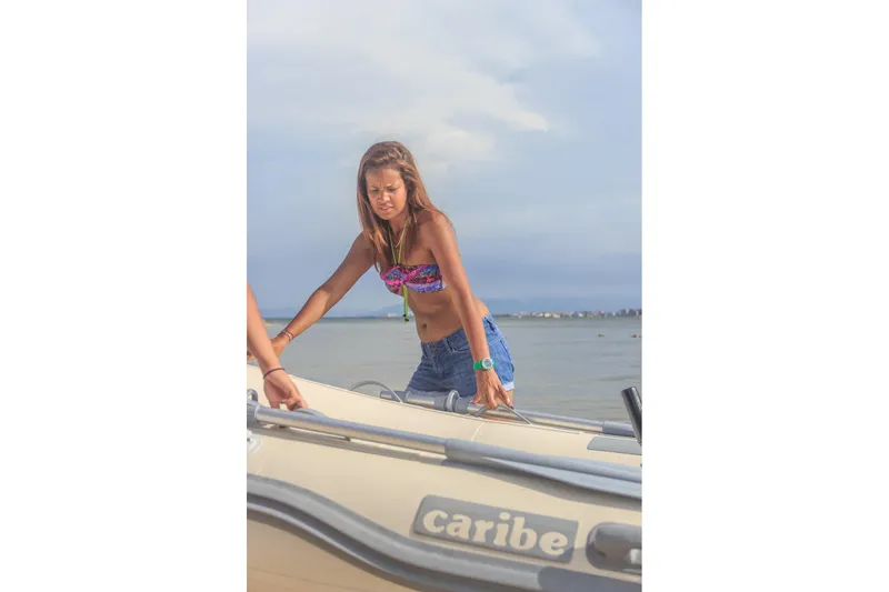 Slide: The Image of Woman in swimwear beside a Caribe C9X boat, 2025 model, on a sunny beach. - 4