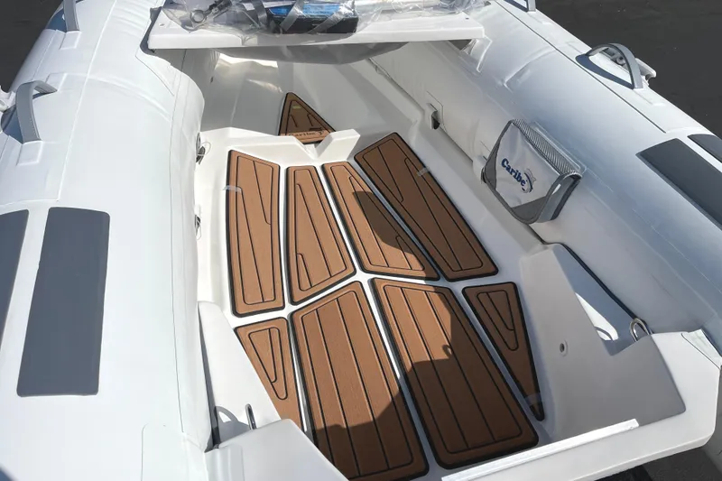 Slide: The Image of 2025 Caribe L8 boat interior with teak-style flooring and white seating. - 16