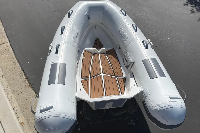 Slide: The Image of Inflatable Caribe L8 boat, 2025 model, with wooden deck, parked on asphalt. - 18
