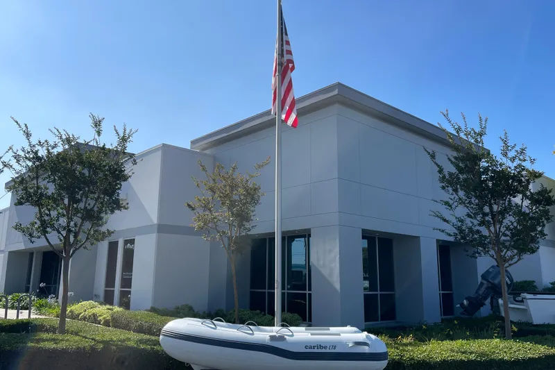 Slide: The Image of Modern building with flagpole and 2025 Caribe L8 inflatable boat in foreground. - 3