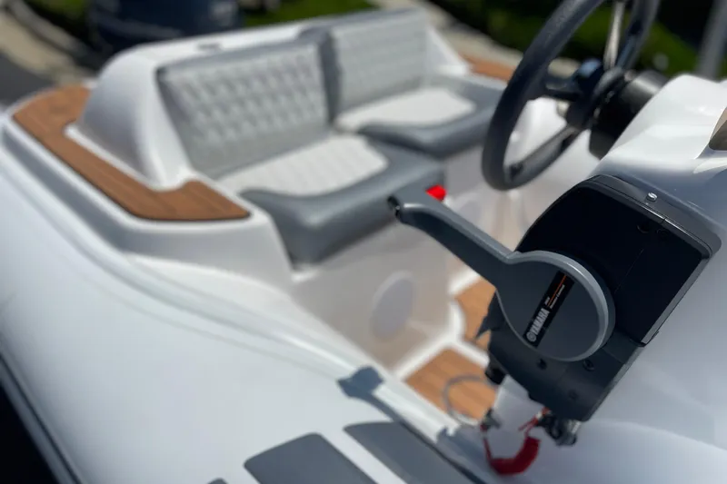 Slide: The Image of 2025 Caribe DL11 boat interior with steering wheel and control lever, featuring sleek design. - 23