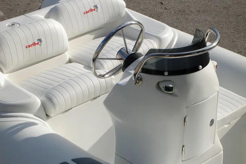 Slide: The Image of 2025 Caribe DL11 boat interior with white seating and sleek steering console. - 37