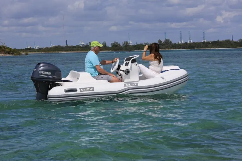 Slide: The Image of Two people on a 2025 Caribe DL11 boat in clear blue water. - 39