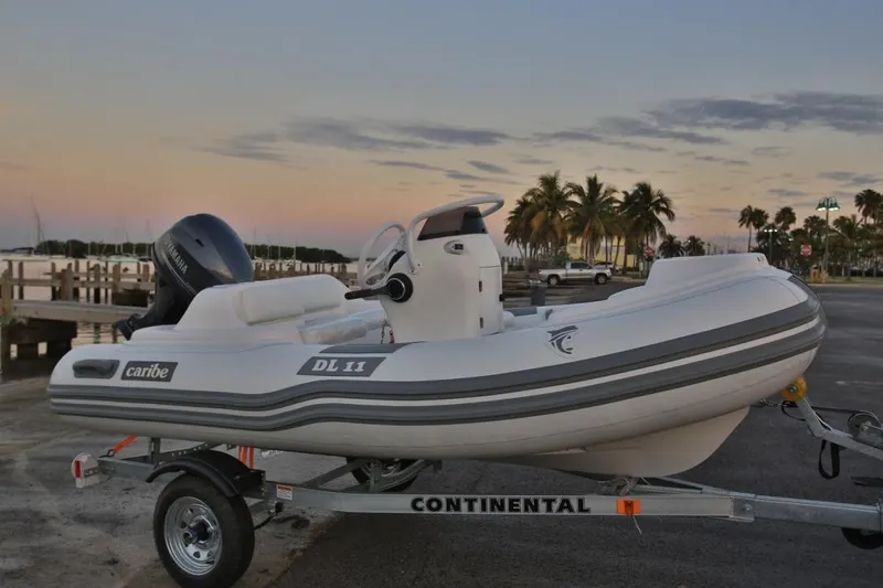 Slide: The Image of 2025 Caribe DL11 inflatable boat on trailer at sunset by the water. - 42
