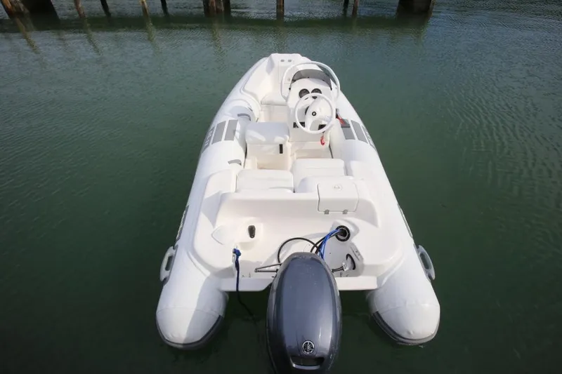 Slide: The Image of 2025 Caribe DL11 inflatable boat on calm water, featuring a sleek design and outboard motor. - 43