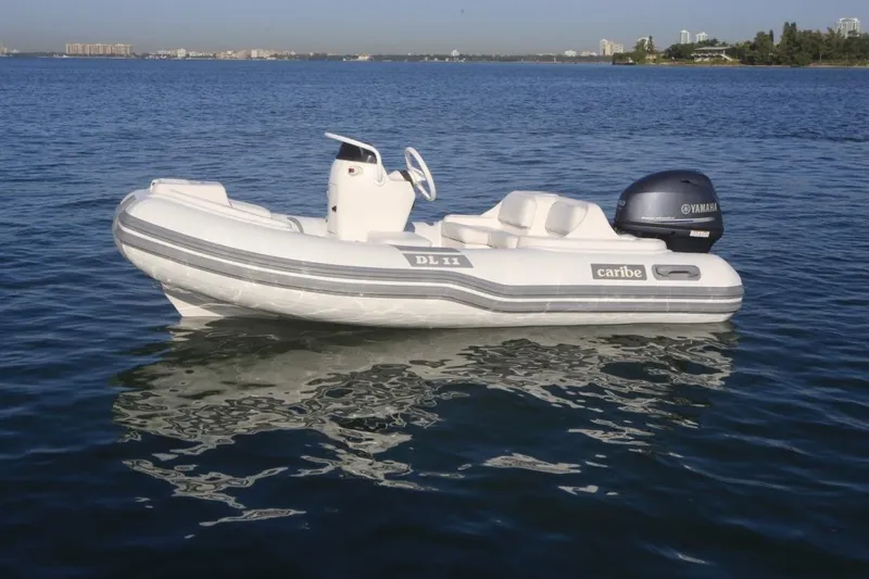 Slide: The Image of 2025 Caribe DL11 inflatable boat on calm water with Yamaha outboard motor. - 46