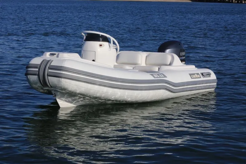 Slide: The Image of 2025 Caribe DL11 inflatable boat on calm water, featuring sleek design and modern outboard motor. - 47