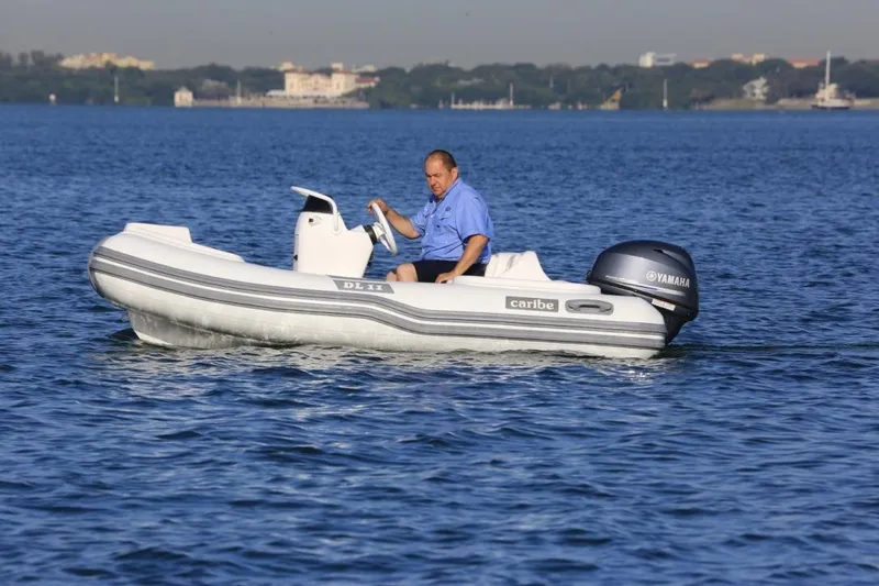 Slide: The Image of Man driving 2025 Caribe DL11 inflatable boat on calm water. - 48