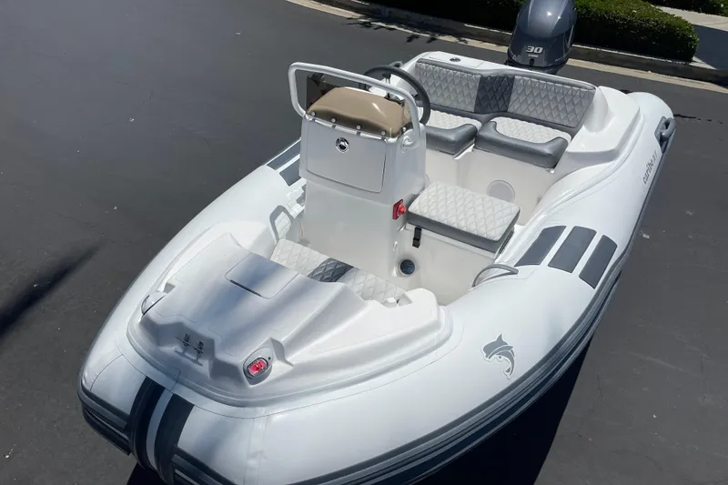 Slide: The Image of 2025 Caribe DL11 inflatable boat with seating, steering console, and outboard motor. - 6