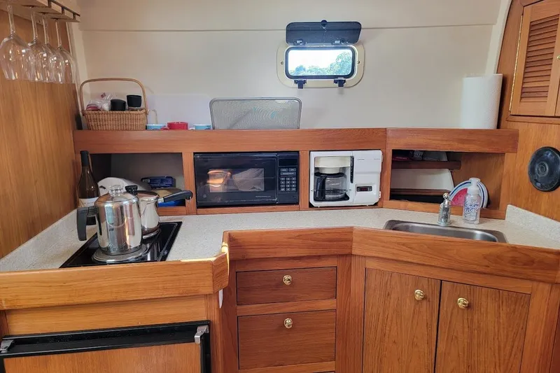 Slide: The Image of Cozy kitchen in 2000 Mainship 34 PILOT boat with wooden cabinetry and modern appliances. - 12