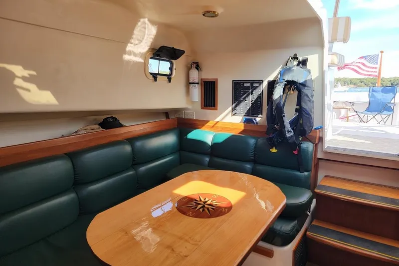 Slide: The Image of Mainship 34 PILOT 2000 interior with green seating, wooden table, and life jacket. - 16