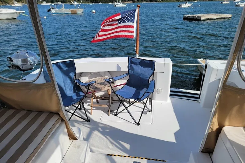 Slide: The Image of Mainship 34 PILOT 2000 boat deck with chairs, table, and American flag on a sunny day. - 18