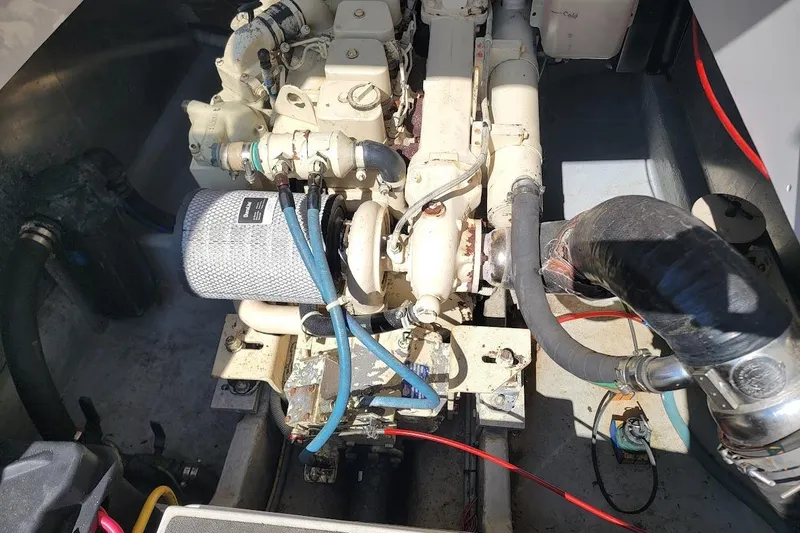 Slide: The Image of Engine compartment of a 2000 Mainship 34 PILOT boat, showcasing mechanical components and hoses. - 23
