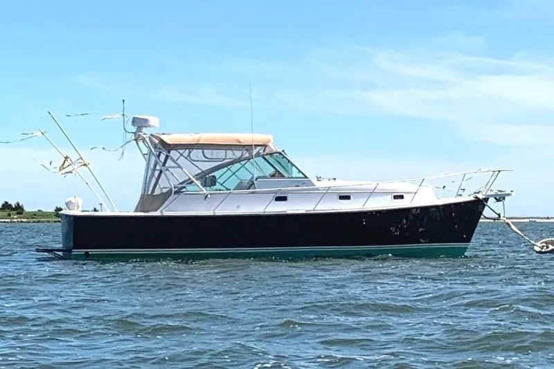 Slide: The Image of 2000 Mainship 34 PILOT boat on calm water under clear blue sky. - 3