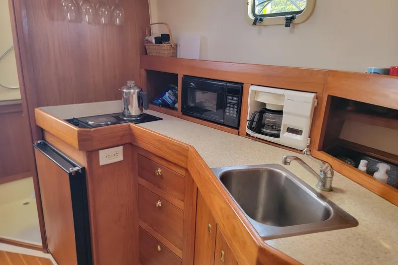 Slide: The Image of 2000 Mainship 34 PILOT yacht kitchen with sink, stove, microwave, and coffee maker. - 7