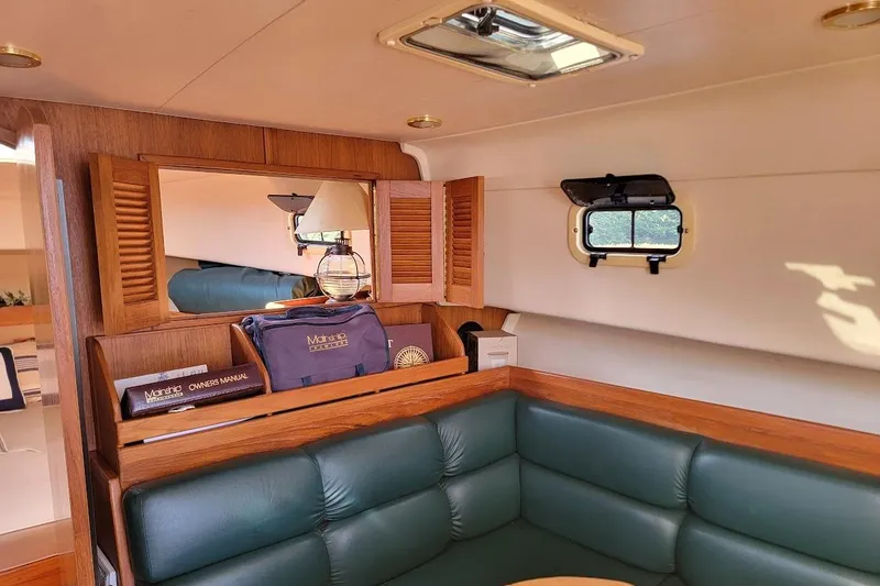 Slide: The Image of Interior of 2000 Mainship 34 PILOT with green seating and wooden accents. - 8