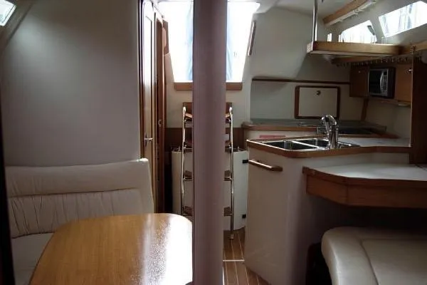 Slide: The Image of Interior of a 2005 Catalina 320 sailboat, featuring a cozy dining area and compact kitchen. - 5