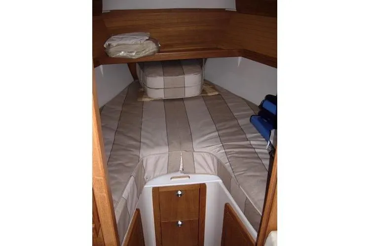 Slide: The Image of 2005 Catalina 320 yacht interior cabin with striped bedding and wooden storage cabinets. - 6