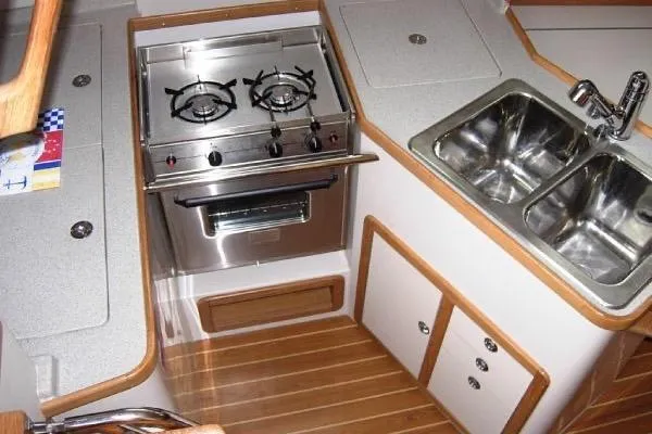 Slide: The Image of Catalina 320 yacht kitchen with stove, dual sink, and wooden cabinetry, 2005 model. - 7