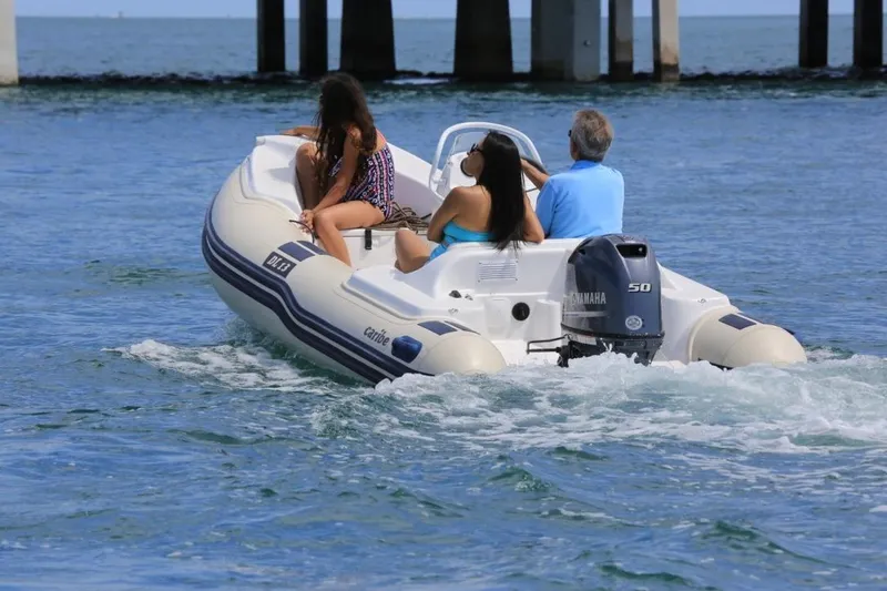 Slide: The Image of People enjoying a ride on a 2025 Caribe DL13 inflatable boat in open water. - 4