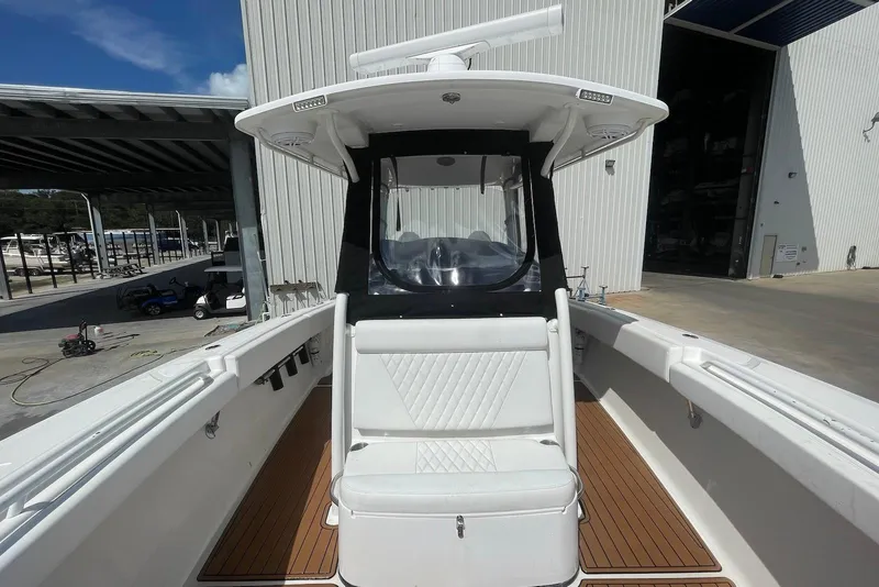 Slide: The Image of 2008 Edgewater 370CC boat with white seating and wooden deck, docked near a warehouse. - 12