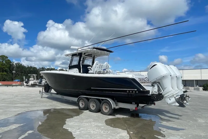 Slide: The Image of 2008 Edgewater 370CC boat on trailer with triple outboard engines under a blue sky. - 4