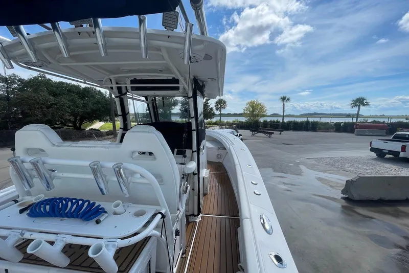 Slide: The Image of 2008 Edgewater 370CC boat docked, featuring spacious deck and rod holders under a clear sky. - 5