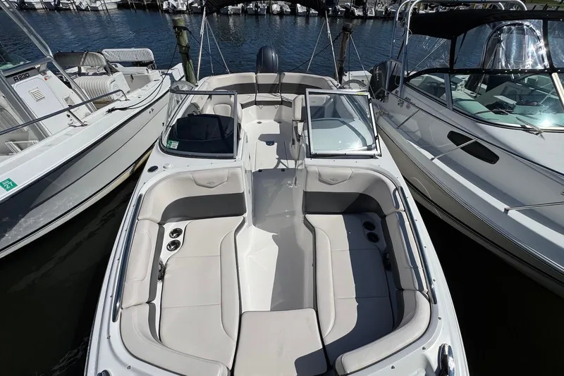 Slide: The Image of 2018 Chaparral 230 Suncoast boat docked between two other boats at a marina. - 19