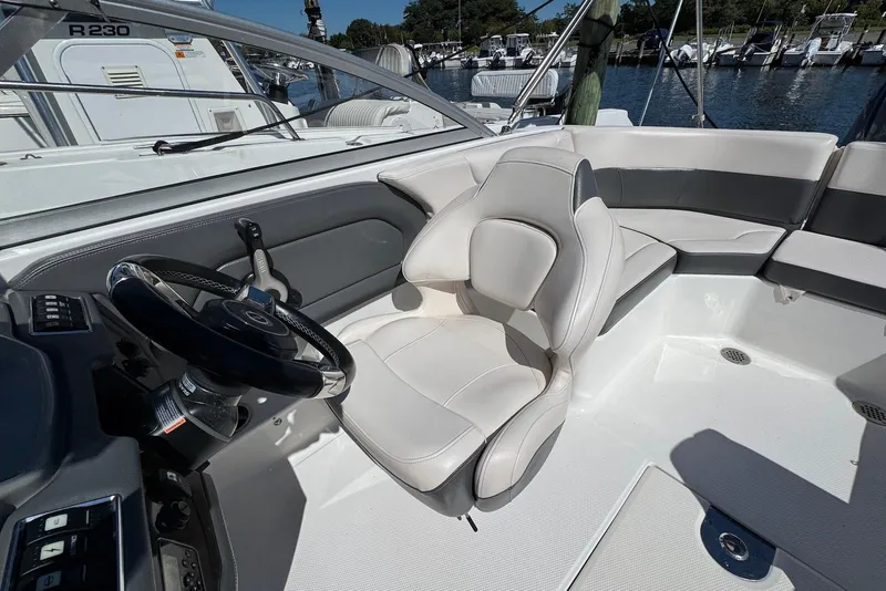 Slide: The Image of 2018 Chaparral 230 Suncoast boat interior with steering wheel and seating, docked at marina. - 8