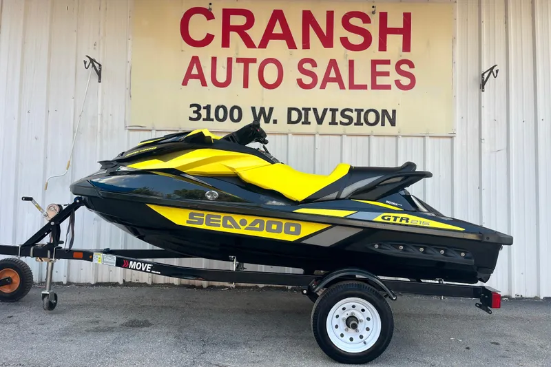 The Image of 2016 Sea-Doo GTR 215 jet ski on trailer by a lake under blue sky. - 0