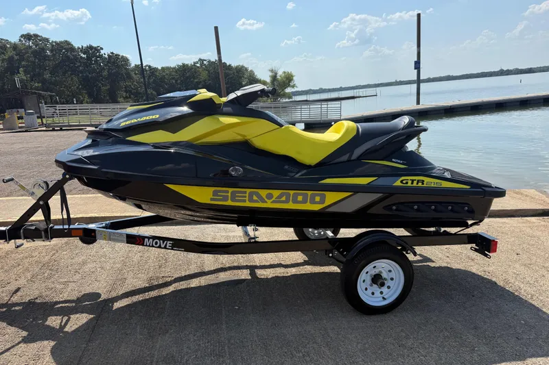 Slide: The Image of 2016 Sea-Doo GTR 215 jet ski on trailer by a lake, featuring yellow and black design. - 41