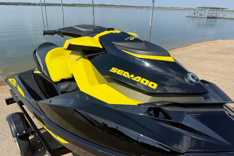 Slide: The Image of 2016 Sea-Doo GTR 215 jet ski in black and yellow, parked by a serene lake. - 55