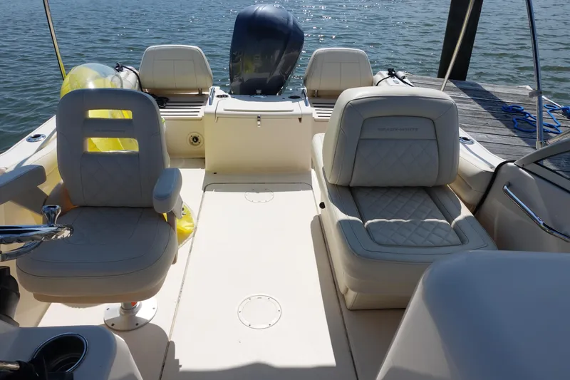Slide: The Image of 2020 Grady-White Freedom 215 boat interior with cushioned seating and steering wheel, docked by water. - 12