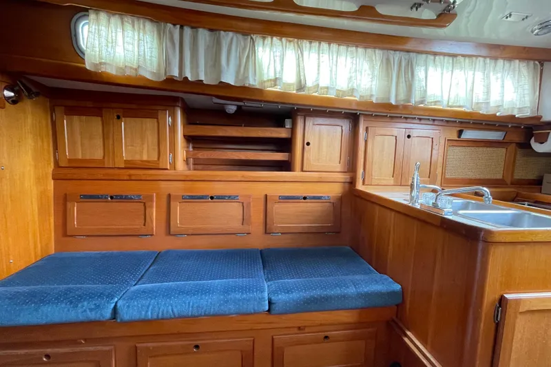 Slide: The Image of Interior of a 1987 Bristol 35.5 sailboat with wooden cabinetry and blue seating. - 18