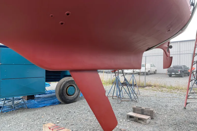 Slide: The Image of 1987 Bristol 35.5 sailboat keel and rudder in dry dock, with support stands. - 4
