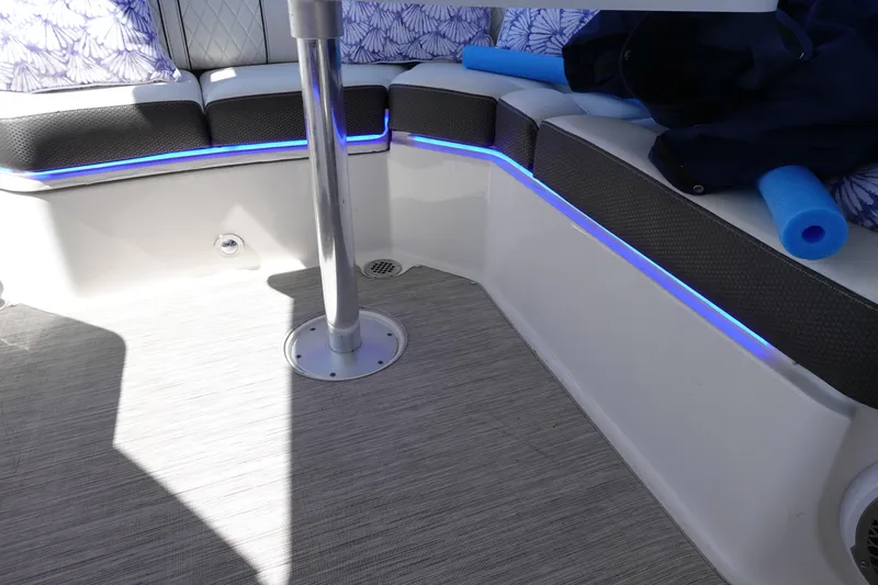 Slide: The Image of 2018 Sea Ray SLX 310 Outboard interior with blue LED lighting and cushioned seating. - 21