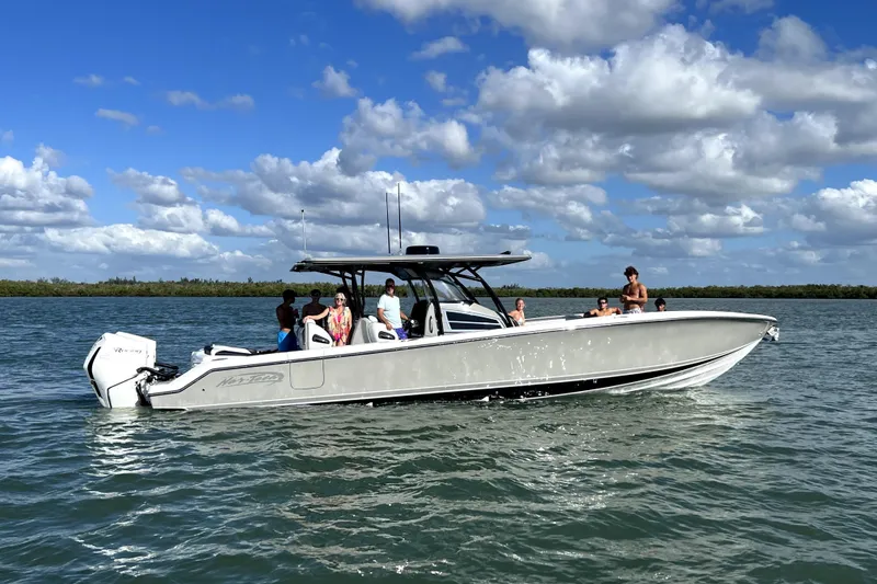 The Image of 2023 Nor-Tech 390 Sport Center Console boat on water with passengers under blue sky. - 0