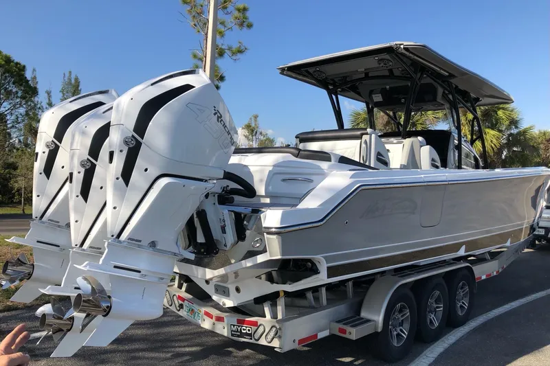 Slide: The Image of 2023 Nor-Tech 390 Sport Center Console boat with triple outboard engines on a trailer. - 2