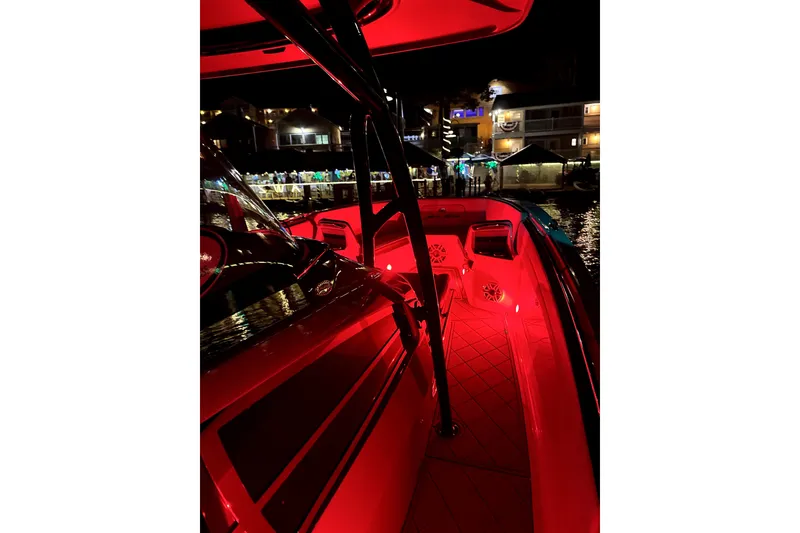 Slide: The Image of 2023 Nor-Tech 390 Sport Center Console with vibrant red interior lighting at night. - 7