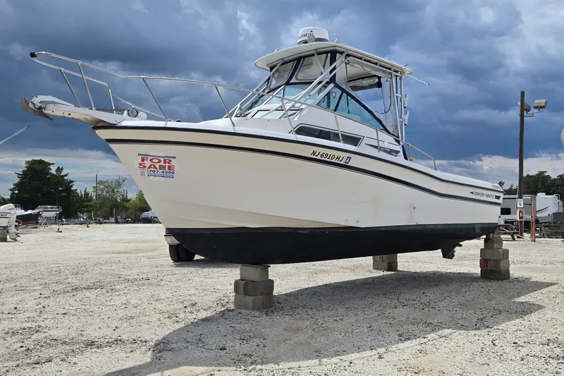 The Image of 1992 Grady-White Sailfish 25 Sportbridge boat for sale, displayed on blocks, under cloudy sky. - 0