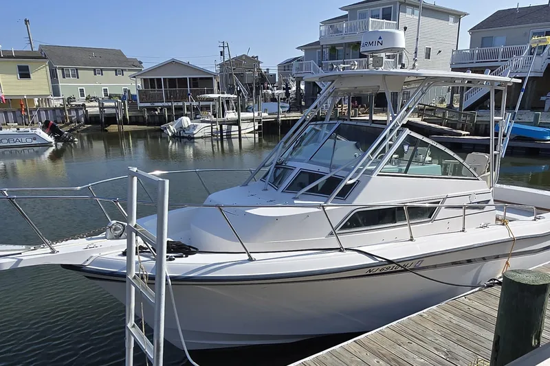 Slide: The Image of 1992 Grady-White Sailfish 25 Sportbridge docked at a marina, surrounded by waterfront homes. - 11