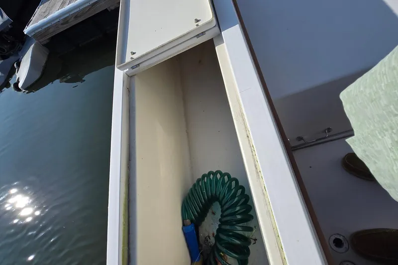Slide: The Image of Open storage compartment on 1992 Grady-White Sailfish 25 Sportbridge boat with coiled hose. - 35