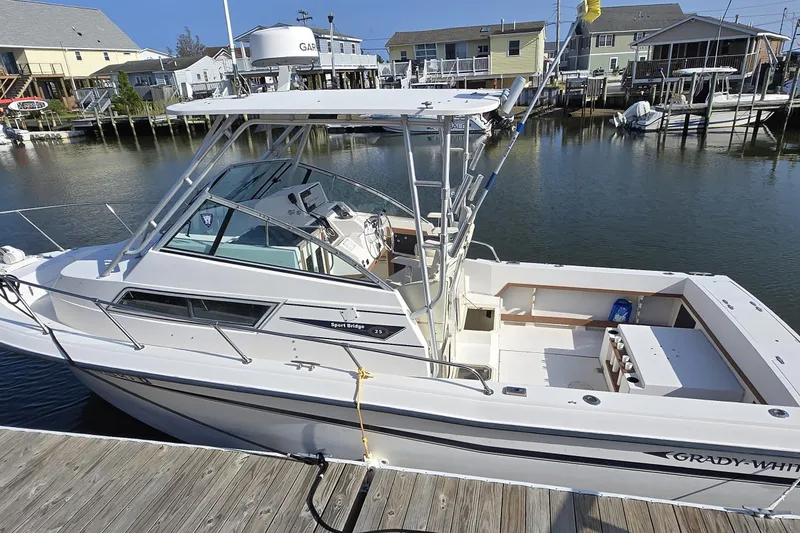 Slide: The Image of 1992 Grady-White Sailfish 25 Sportbridge docked at marina, showcasing spacious deck and cabin. - 9