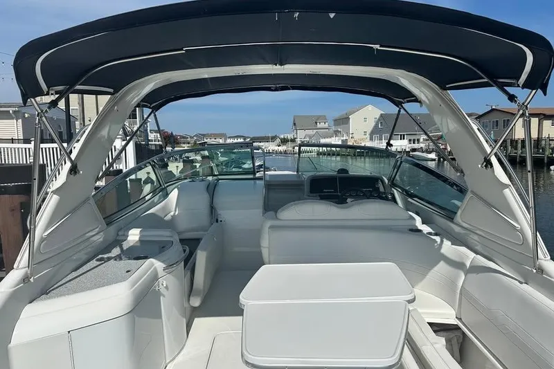 Slide: The Image of 2004 Formula 330 Sun Sport boat interior with seating and canopy, docked in a residential area. - 12